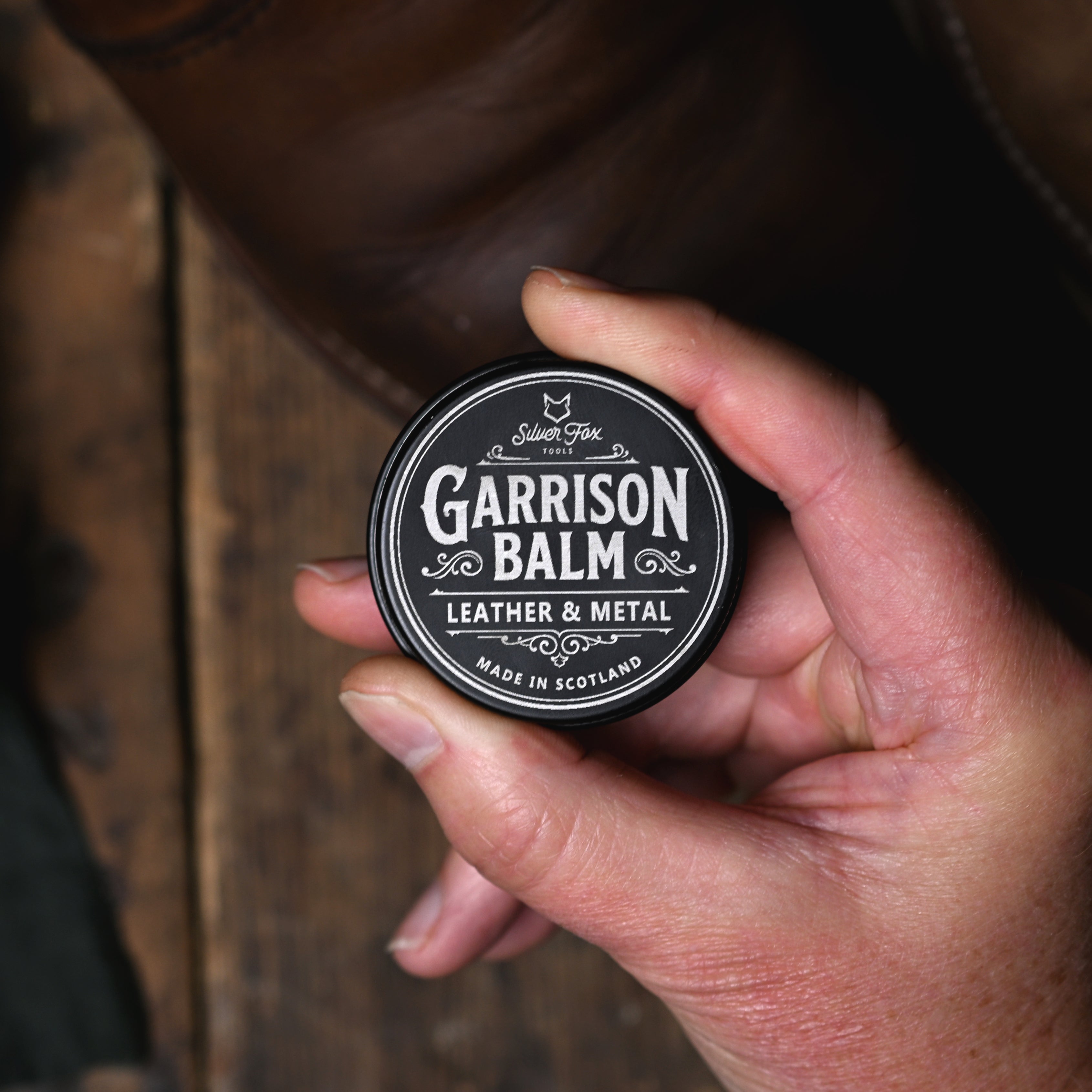 A tin of Garrison Balm from Silver Fox Tools being held in a hand for display.