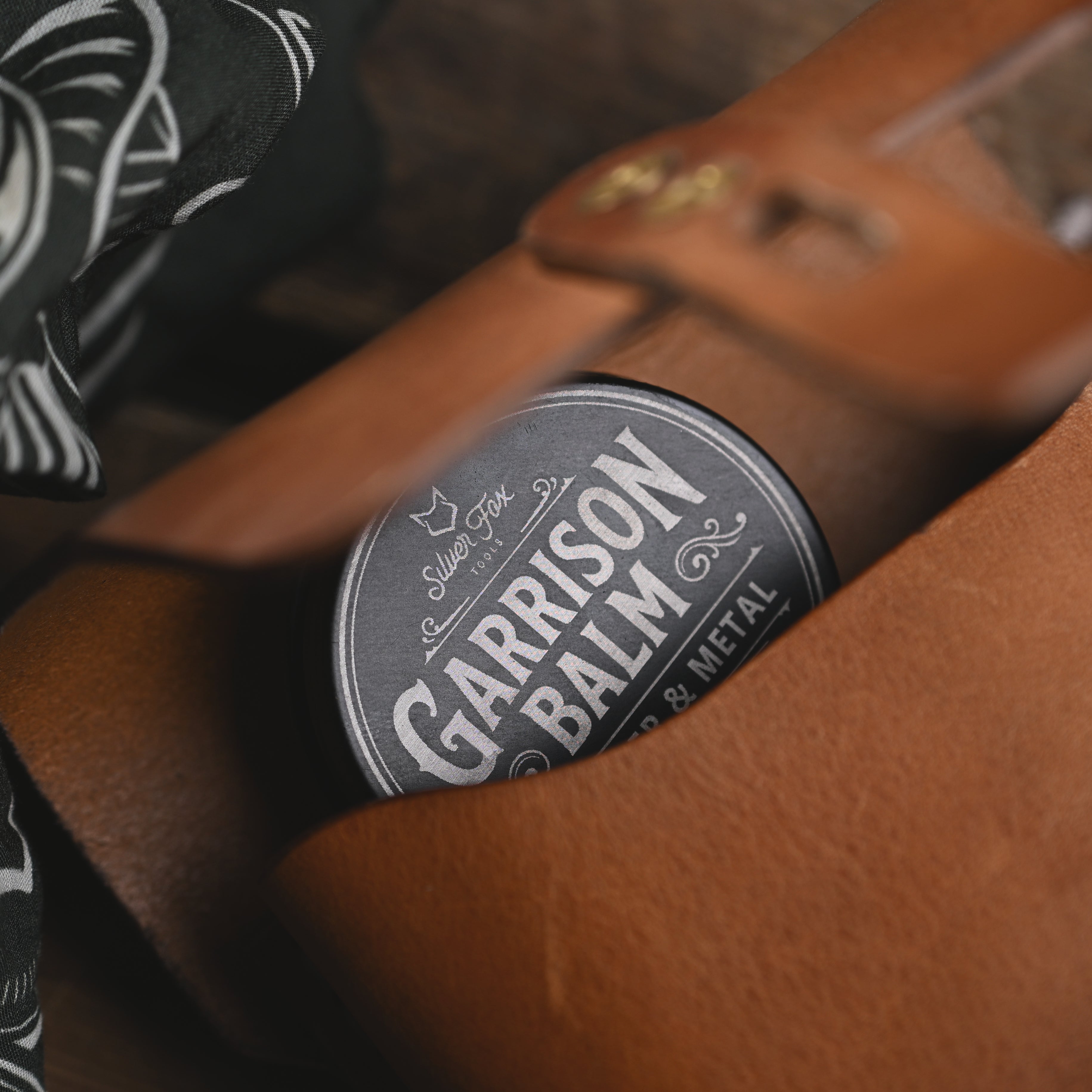 A tin of Silver Fox Tools Garrison Balm tucked inside a leather pouch.
